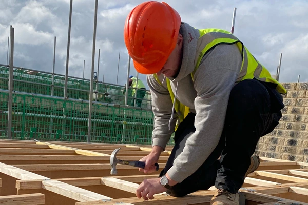 Carpenter installing timber floor joists during house construction