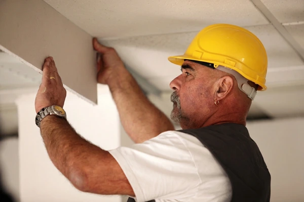 Dry lining fixer placing plasterboard on a wall