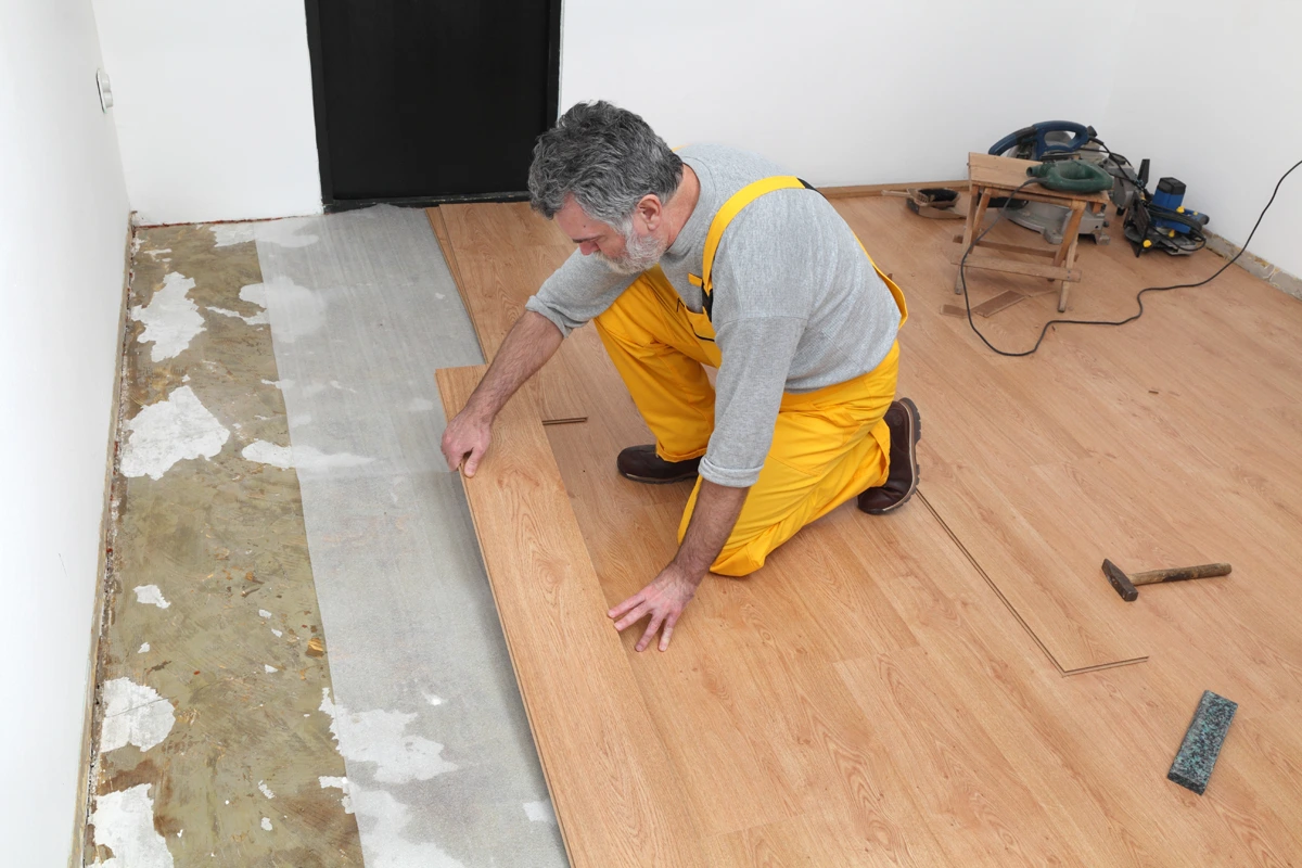 Multi-trade worker fixing flooring as part of building refurbishment