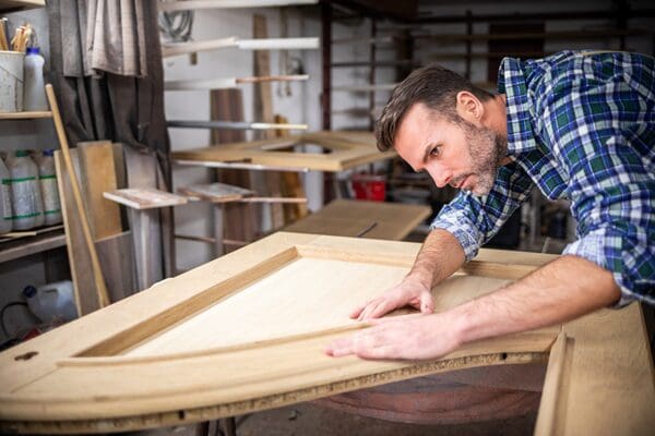 Bench joiner making a timber door frame in a workshop